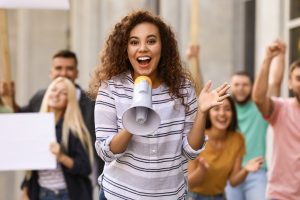 an excited woman with a megaphone trying to promote herself to a crowd